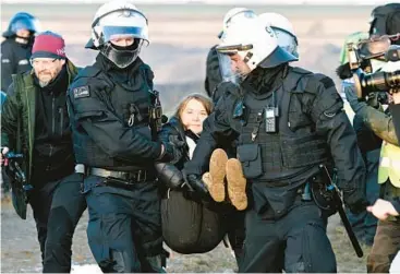  ?? FEDERICO GAMBARINI/DPA ?? Carried away: Police officers carry Swedish climate activist Greta Thunberg from the edge of the Garzweiler open pit coal mine Tuesday in Luetzerath, Germany. Thunberg was among hundreds who resumed protests throughout the German state of North Rhine-Westphalia. Demonstrat­ors are against the destructio­n of a village to expand the mine.
