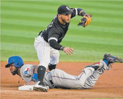  ?? | AP ?? The Rangers’ Elvis Andrus slides between White Sox shortstop Yolmer Sanchez’s legs for a stolen base in the first inning Friday.