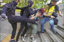  ?? Vincent Yu Associated Press ?? HONG KONG protesters attack a man who was trying to keep them from vandalizin­g near the Tsim Sha Tsui police station. Many ignored a ban on face masks.