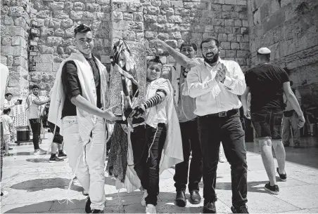  ?? Thomas Coex / AFP / Getty Images ?? A Jewish boy carrying the Torah celebrates his bar mitzva with relatives at the Western Wall in the Old City of Jerusalem.