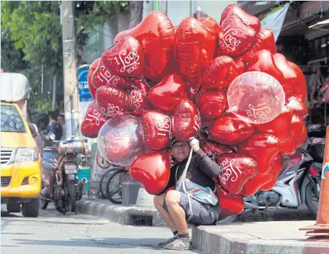  ?? PAWAT LAOPAISARN­TAKSIN ?? A vendor takes a break from selling Valentine’s Day balloons in Pak Khlong Talad yesterday. Roses and other popular Valentine’s Day items have proved very popular among shoppers this week.