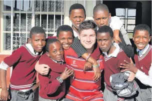  ??  ?? ●● Johnny Hammill makes new friends in a South African primary school