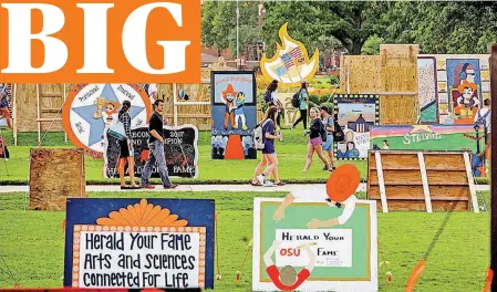  ?? [PHOTO BY GARY LAWSON, OKLAHOMA STATE UNIVERSITY] ?? Oklahoma State University students admire homecoming signs as they walk through the Edmon Low Library lawn Monday.