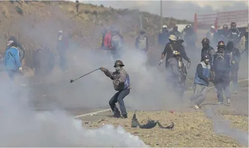  ??  ?? VIOLENCE: Independen­t miners clash with the police as they run from clouds of tear gas during protests in Panduro, Bolivia on Thursday