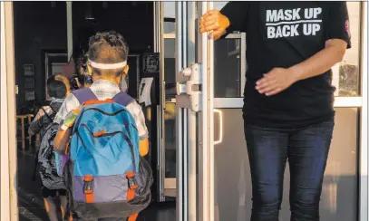  ?? Mikala Compton The Associated Press ?? A staff member holds the door open for children Tuesday on the first day of school at Goodwin Frazier Elementary School in New Braunfels, Texas. The number of Americans newly diagnosed with the coronaviru­s is falling.