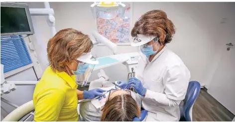  ?? FOTO: HANS-JUERGEN BAUER ?? Zahnärztin Petra Koch (r.) und Assistenti­n Silke Thomsen tragen bei der Behandlung Schutzhand­schuhe, Mund- und Gesichtssc­hutz.