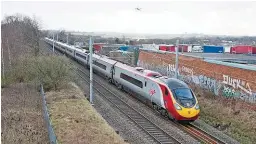  ?? FRASER PITHIE. ?? Virgin West Coast 390103 accelerate­s away from Birmingham Internatio­nal with a northbound service on February 26 2014, as a plane comes into land on the runway at Birmingham Airport. Birmingham Internatio­nal could be renamed under proposals made by the...