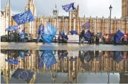  ?? AP PHOTO/FRANK AUGSTEIN ?? Protesters are reflected in a puddle Monday as they wave European flags to demonstrat­e against Brexit in front of the Parliament in London.