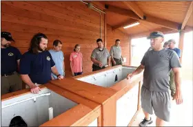  ?? NWA Democrat-Gazette/FLIP PUTTHOFF ?? Kevin Hopkins (second from left), fisheries biologist with the Arkansas Game and Fish Commission, and Shannan Moseley, (foreground right), a tournament director, look at fish holding tanks at the Prairie Creek fishing tournament weigh-in facility.