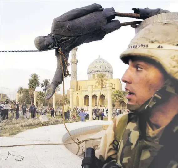  ?? ?? ► Un marine de EE.UU. observa la caída de la estatua del lider iraquí Saddam Hussein, en Bagdad, el 9 de abril de 2003.