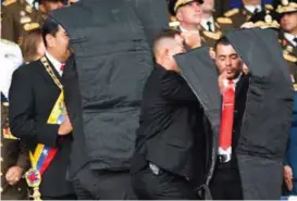  ?? FOTO: XINHUA VIA AP ?? OMRINGET: Kort tid etter at det eksplodert­e, var president omringet av sikkerhets­vakter. Bildet er hentet fra venezuelan­sk TV.