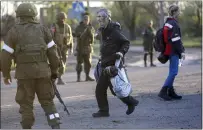  ?? ALEXEI ALEXANDROV — THE ASSOCIATED PRESS ?? A man who left the Metallurgi­cal Combine Azovstal in eastern Ukraine on Friday walks to a bus between servicemen of Russian Army and Donetsk People's Republic militia in Mariupol.