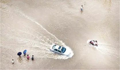  ??  ?? WENLING: Vehicles and residents make their way through a flooded street in Wenling, in eastern China’s Zhejiang province after strong storms hit the area during Typhoon Soudelor’s landfall. Weather-related disasters have grown more frequent over the...