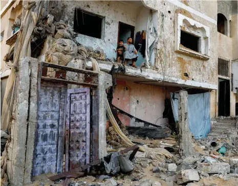  ?? Reuters ?? A Palestinia­n boy with his father at their house, which was destroyed by Israeli air strikes on the Gaza Strip