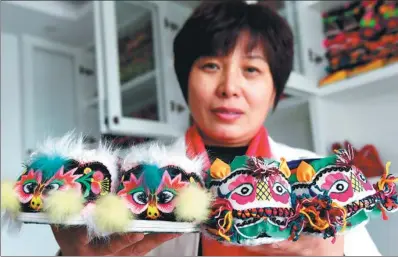  ?? PHOTOS BY ZHU XIANG / XINHUA ?? Hu Shuqing displays two pairs of tiger-head shoes from her collection at her home in Zhengzhou, Henan province.