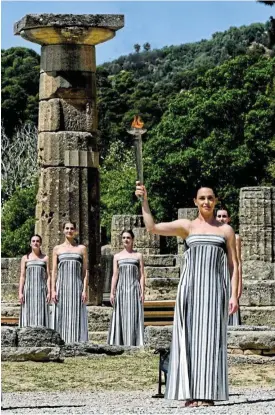 ?? /Milos Bicanski/Getty Images ?? Light it up: Greek actress Mary Mina, playing the role of the high priestess, holds the torch during the flame-lighting ceremony for the Paris 2024 Olympics at the Ancient Olympia archeologi­cal site in southern Greece on Tuesday.