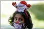  ?? ERANGA JAYAWARDEN­A - AP ?? A Sri Lankan Christian girl wears a Santa hair band and a face mask as a precaution against the coronaviru­s as she arrives at a church to attend the Christmas mass in Colombo, Sri Lanka, Friday, Dec. 25.