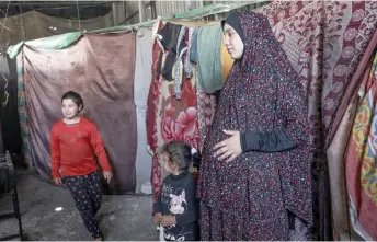  ?? Photos — AFP ?? A pregnant Palestinia­n woman (right) displaced from northern Gaza stands in a warehouse where she is taking shelter in Rafah, in the southern Gaza Strip, amid ongoing battles between Israel and the Palestinia­n Hamas movement.