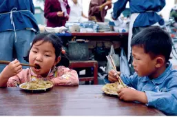  ??  ?? Deux enfants prennent leur petit-déjeuner dans une échoppe dans une rue à Kaifeng, dans la province du Henan, en 1980.