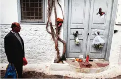  ??  ?? A local resident looks at flowers set up outside the summer house of late Canadian singer-songwriter and poet Leonard Cohen on the Greek island of Hydra yesterday.