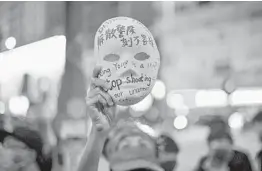  ?? PHILIP FONG/GETTY-AFP ?? A woman holds a mask with slogans as protesters gather outside Mong Kok police station Saturday. Hong Kong’s leader, Carrie Lam, outlawed face coverings Friday.