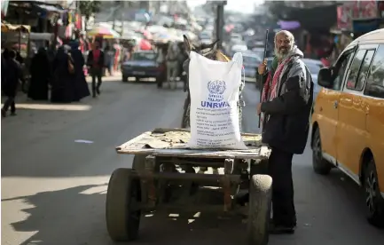  ?? (Ibraheem Abu Mustafa/Reuters) ?? A MAN STANDS next to a cart carrying a sack of flour distribute­d by UNRWA in the Khan Yunis refugee camp in the Gaza Strip earlier this month.