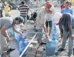  ??  ?? SHORTAGE OF SUPPLIES: People queue for water at a temporary camp in Palu yesterday.