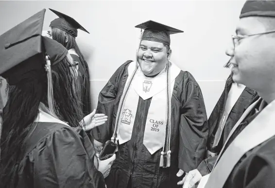  ?? Melissa Phillip / Staff photograph­er ?? Thurgood Marshall High School students Anna Majano, 18, from left, Jose Lopez, 19, and Carlos Lopez, 18, wait in line during their graduation ceremony at Smart Financial Centre. Marshall is one of just two high schools in Fort Bend with a D- rating on this year’s school report card, according to the nonprofit Children At Risk