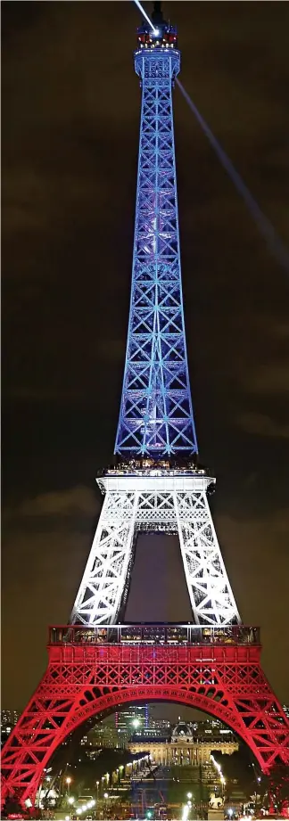  ??  ?? Tribute to the victims: The Eiffel Tower lit up in the French colours yesterday