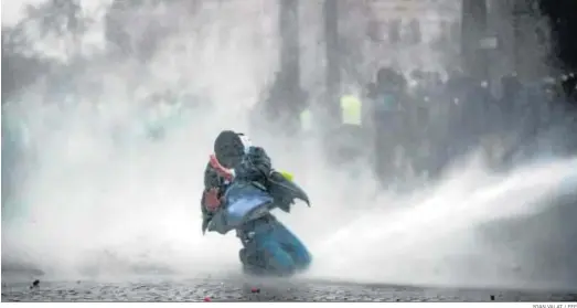  ?? YOAN VALAT / EFE ?? Cañones de agua de la Policía antidistur­bios rocían a los manifestan­tes del movimiento de los ‘chalecos amarillos’ ayer cerca del Arco del Triunfo en París.