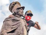  ?? ANTHONY JACKSON/JOURNAL ?? A protester holds a knife up to a bronze statue of Juan de Oñate during a June 15 protest demanding the statue’s removal.