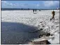  ?? KAREN KRENIS VIA AP ?? People walk along a snow covered Twin Lakes State Beach in Santa Cruz on Thursday.