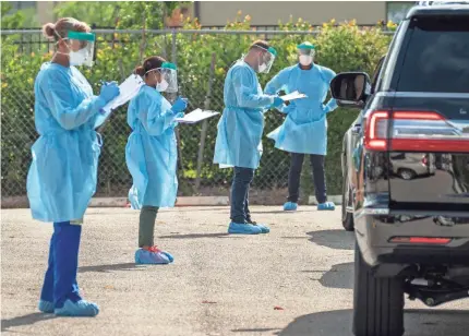  ?? GREG LOVETT/THE PALM BEACH POST ?? Health care workers screen patients who will be tested for COVID-19 at the FoundCare drive-through testing station in Palm Springs, Fla., on Thursday.