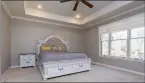  ??  ?? The carpeted master bedroom offers an attractive tray ceiling, recessed lighting and a ceiling fan.