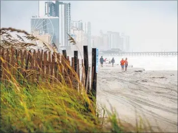  ?? Cristobal Herrera EPA/Shuttersto­ck ?? PEOPLE walk on the sand on Saturday in Myrtle Beach, S.C., among those who ignored the evacuation order.