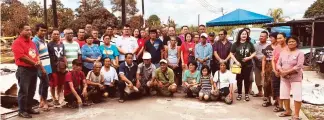  ??  ?? DAP members led by Leon (standing, seventh left) in a photo-call with the fire victims.