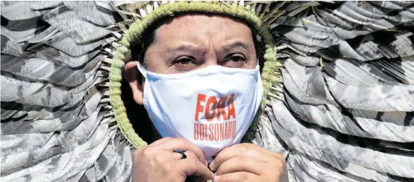  ?? FOTO: EVARISTO SA/AFP ?? Kretan Kaingang, Vertreter eines indigenen Stammes, bei einer Demonstrat­ion gegen Brasiliens Präsident Bolsonaro in Brasilia. „Weg mit Bolsonaro!“steht auf seinem Mund-Nasen-Schutz.