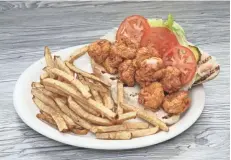  ??  ?? The shrimp po’ boy has lightly battered shrimp, lettuce, tomato, pickles and spicy mayo. It’s served with house-cut fries.