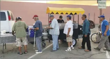  ?? COURTESY PHOTO ?? Pinki’s hot Dogs prepares freshly cooked chili dogs for a line of homeless people on Saturday in Calexico.