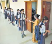  ??  ?? Students undergo thermal scanning and get their hands sanitized as they arrive at a school that was reopened in Thane on Tuesday