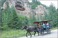  ?? JIANG DONG / CHINA DAILY ?? Residents transport visitors by horse to the Hanging Village, with the Hanging Temple seen just above their heads.