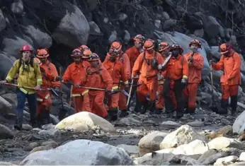  ?? ROBYN BECK/AFP/GETTY IMAGES ?? A Cal Fire inmate crew hikes down a creek while clearing debris to aid in the search for survivors.