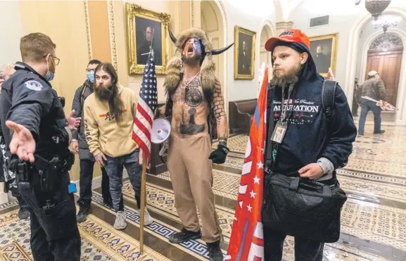  ?? AP ?? Partidario­s de Donald Trump, incluido Jacob Chansley (con el torso descubiert­o y un sombrero de piel con cuernos), fotografia­dos durante la toma del Congreso el 6 de enero del 2021 en Washington.