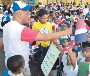  ??  ?? José Domínguez, presidente del club Mauricio Báez, mientras repartía banderines a niños,