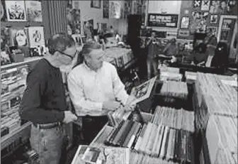  ?? DAY FILE PHOTO ?? Bill Young, left, of East Lyme and Mark Maillett of Niantic examine an album while the CBYD (Call Before You Dig) Trio play in the background at a previous Record Store Day, an internatio­nal celebratio­n of independen­t record stores, at Telegraph Record Store in New London.