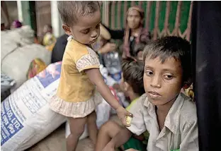  ?? AP Photo/Gemunu Amarasingh­e ?? Two-year-old Noyem Fatima offers a piece of banana to her elder brother, Yosar Hossein, 7, Oct. 2 as they sit on a sidewalk with their belongings in Leda, Bangladesh. Hossein carried Noyem for seven days as they fled from their village in Myanmar to a...