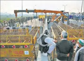  ?? SANCHIT KHANNA/HT PHOTO ?? Demonstrat­ors stand behind barricades and concertina wire as more barriers are put in place at Ghazipur on Saturday.