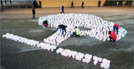  ?? ZHENG HUANSONG / XINHUA ?? Environmen­talists stage a tree design with candle-holding paper bags in Brussels on Dec 14, urging people to come “together for forests”.