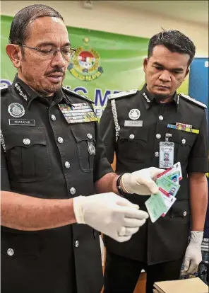  ?? — Bernama ?? Forbidden craft: Mustafar (left) with Federal Territory Immigratio­n director Hamidi Adam showing a few of the fake CIDB cards and the foreign workers temporary e-cards made by the syndicate, at the press conference at the Home Ministry Complex in Kuala...