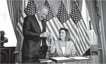  ?? J. SCOTT APPLEWHITE/AP ?? Senate Minority Leader Chuck Schumer joins House Speaker Nancy Pelosi as she signs the budget package Thursday.